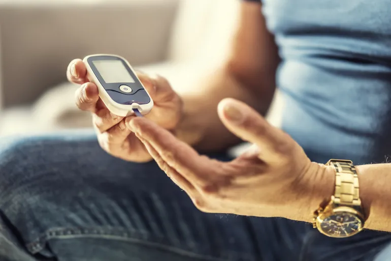 Mid adult Man Checking Blood Sugar Levels by Glucose Meter at Home in the Living Room. Medicine, Diabetes, Glycemia, Health Care and People Concept