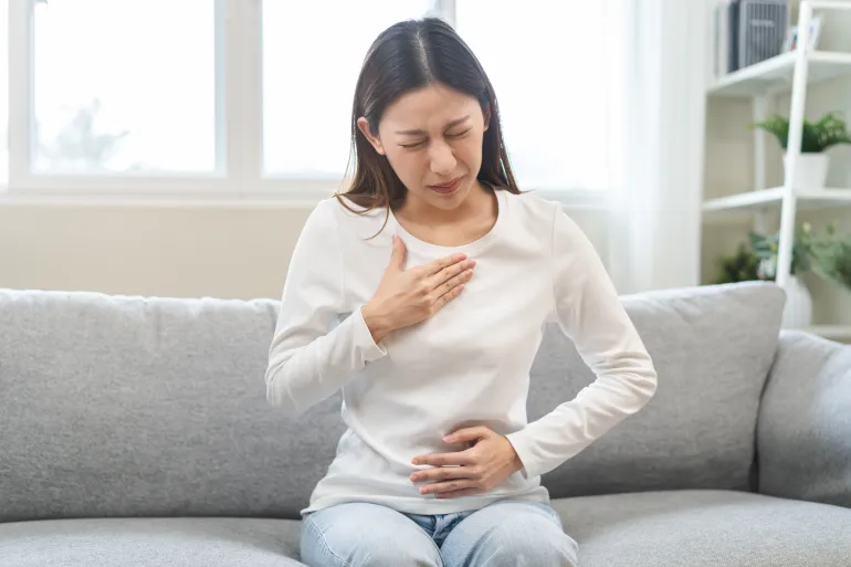 Acid reflux disease, suffer asian young woman have symptom gastroesophageal, esophageal, stomach ache and heartburn pain hand on chest from digestion problem after eating food, Healthcare medical concept