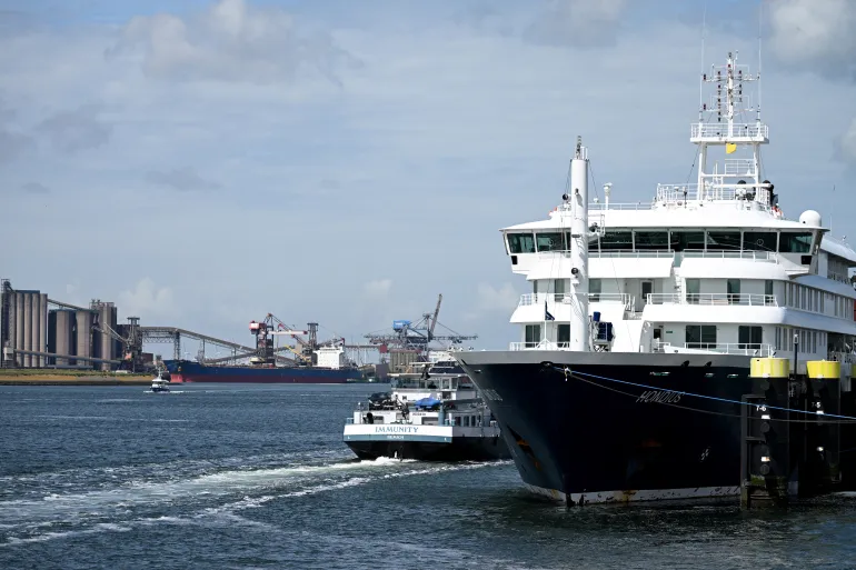 The "Immunity" inland tanker (L) sails past the docked Dutch Hantavirus-hit cruise ship MV Hondius at the port of Rotterdam on May 18, 2026.