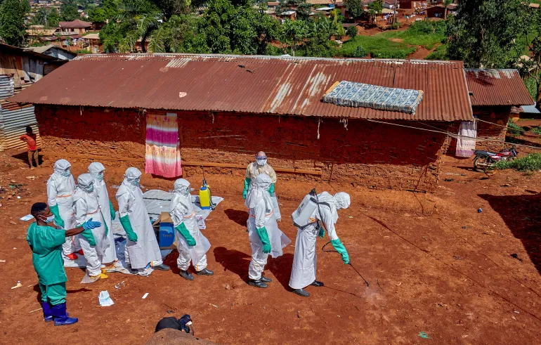 FILE PHOTO: Red Cross workers wearing personal protective equipment walk in a formation as they disinfect the ground outside the house of an unidentified man who died of Ebola, before retrieving his body, as aid agencies intensify efforts to contain a new Ebola outbreak involving the Bundibugyo strain, in Quartier Shuni 1, a residential sector in Mongbwalu, Djugu Territory of Ituri province, Democratic Republic of Congo, May 24, 2026. REUTERS/Gradel Muyisa Mumbere/File Photo