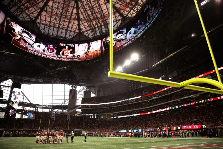 FILE - In this Dec. 31, 2017, file photo, the Atlanta Falcons and Carolina Panthers huddle during the first half of an NFL football game, in Atlanta. Atlanta's new $1.5 billion stadium is about to be on perhaps its largest national stage for the Monday, Jan. 8, 2018, College Football Playoff title game, fans say the glitzy facility is living up to the hype despite a series of construction setbacks that delayed its opening. (AP Photo/David Goldman, File)