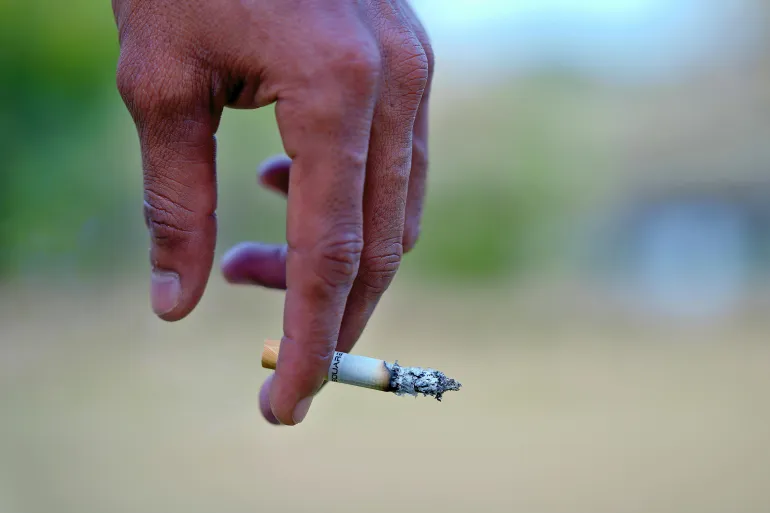Detailed image of a hand holding a cigarette, signifying smoking habits and health risks.