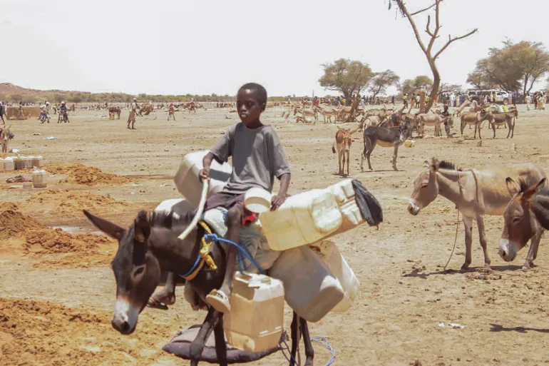 A young child returns from a trip to fetch water that saps his strength... Source: Al Jazeera Net