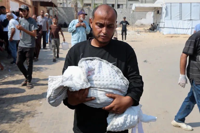 Ahmed Abu Haleeb, the father of Palestinian baby Zainab Abu Haleeb, who died due to malnutrition, according to health officials, holds her body, in Khan Younis, southern Gaza Strip, July 26, 2025. REUTERS/Ramadan Abed