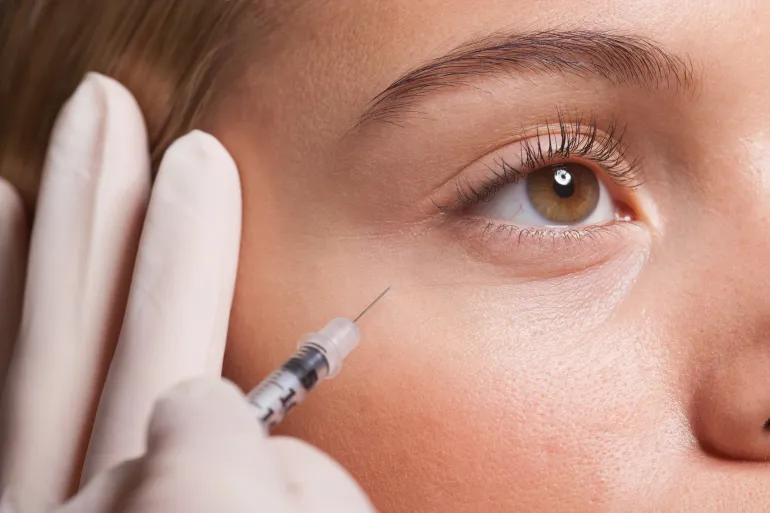 Close up of woman receiving botox injection under eye - stock photo