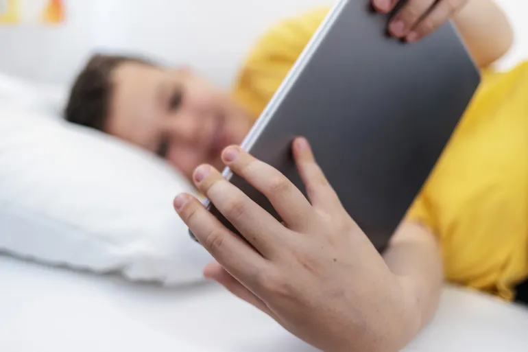 Young boy enjoys screen time in his bed, using a tablet computer to explore the digital world. Child using gadget, education and development. by Jelena Stanojkovic @Adobe Stock