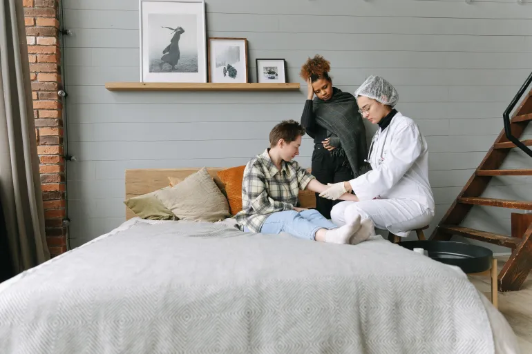 A doctor offers supportive care to a patient in a cozy bedroom setting, fostering recovery.