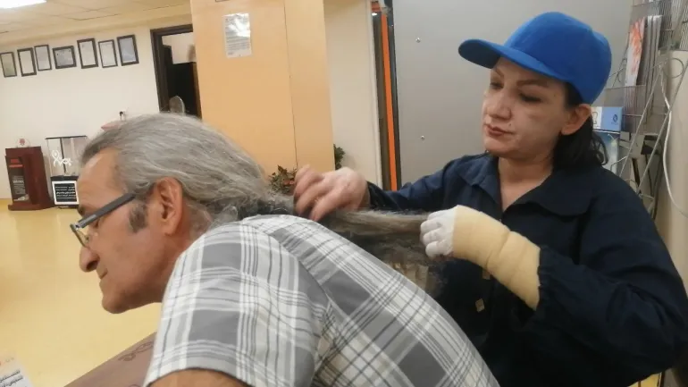 Linda takes care of her husband's hair after losing her hair due to cancer (Al Jazeera).