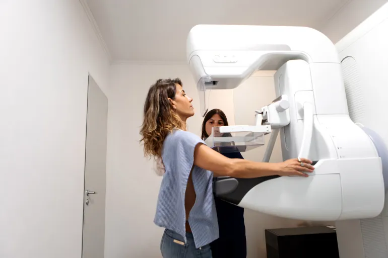 Young female radiology technician explaining and performing a breast exam on a middle-aged female patient using a state-of-the-art mammography machine in a medical clinic - Buenos Aires - Argentina